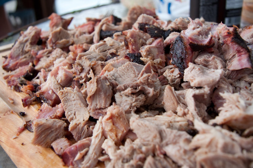 a pile of cooked and chopped pork on a wooden cutting board